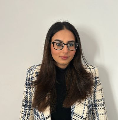 Professional woman with long hair and glasses in a checkered blazer.