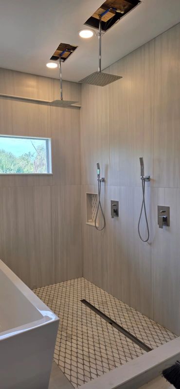 Modern dual shower heads with handheld sprays in a sleek tiled bathroom shower area.