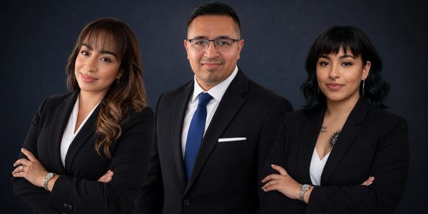Three professionals in formal attire posing confidently against a dark background.