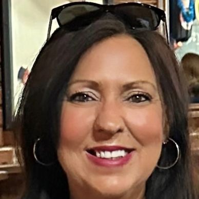 Smiling woman with dark hair and hoop earrings.