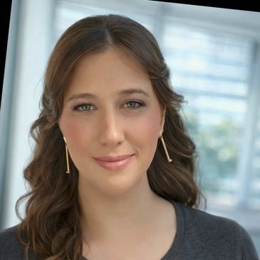 Close-up of a smiling woman with wavy brown hair and gold earrings.