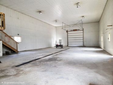 Spacious empty warehouse with high ceiling and a large garage door.