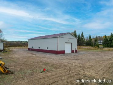 Large white and red warehouse building on a dirt lot with blue sky.
