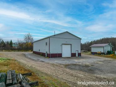 A large industrial building with a smaller adjacent structure in a rural setting.