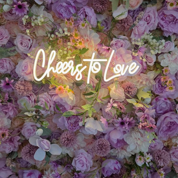 A neon sign saying 'Cheers to Love' on a purple floral wall.