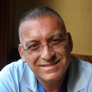 Smiling man wearing glasses and a light blue shirt.