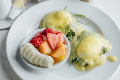 Spinach egg benedict with a side of small fruit cup.
