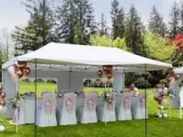 Bridesmaids in matching dresses under a white canopy outdoors.