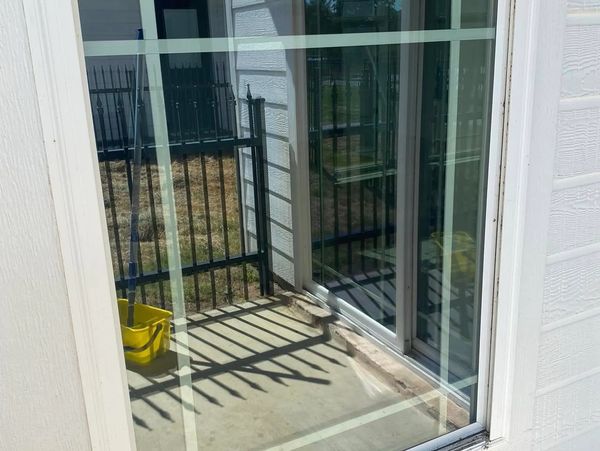 Reflection of a balcony with a yellow mop bucket on a glass window.