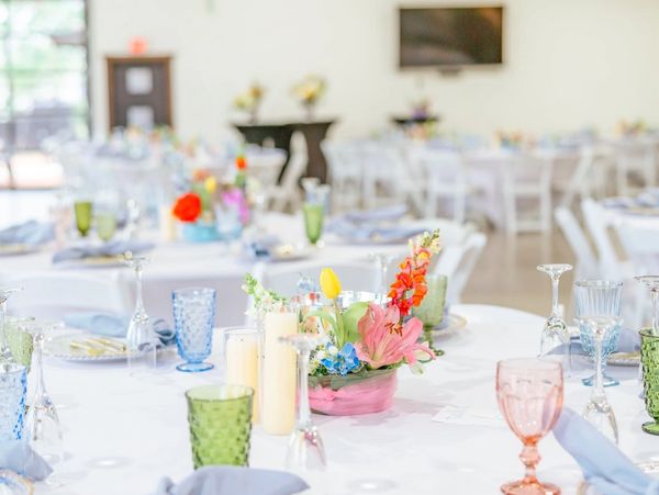 Elegant table setting with pastel-colored glassware and floral centerpiece at a bright event venue.
