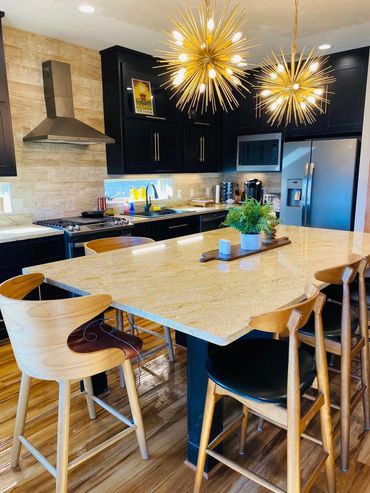 Modern kitchen with wooden chairs and bright pendant lights.