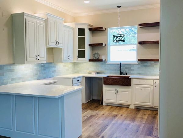 Bright kitchen with white cabinets, wood floors, and decorative farmhouse sink.