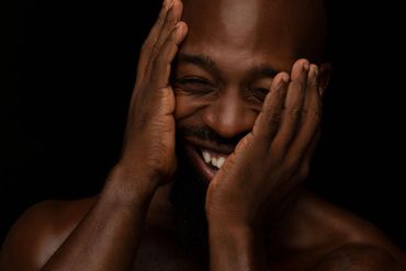Happy African American Man Smiling with his hands partially covering his face