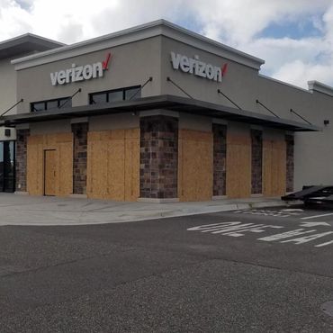 A Verizon store with boarded-up windows and doors on a cloudy day.
