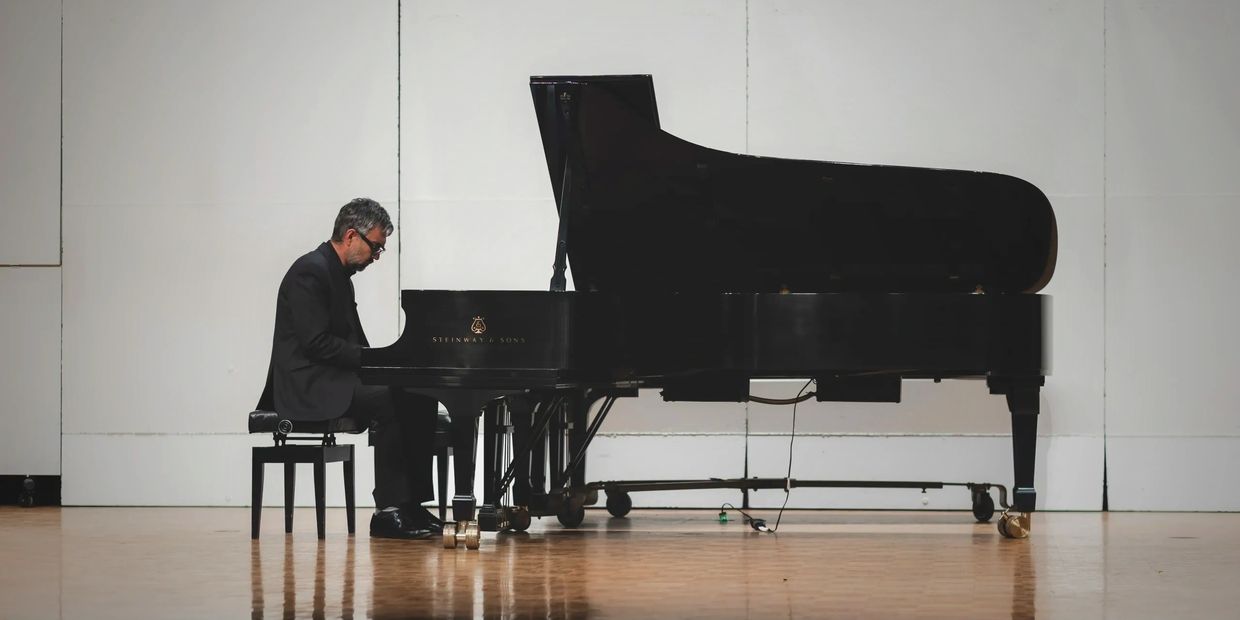 Our founder, Josh Janitell playing grand piano on stage at Hoag Hall.