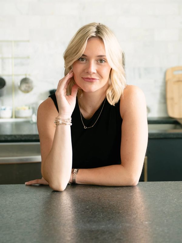 Blonde woman sitting at kitchen counter, smiling.