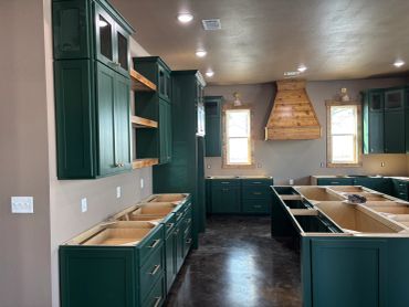 Kitchen with green cabinets and wooden accents.
