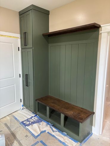 Green built-in storage bench with wooden top and tall cabinets.