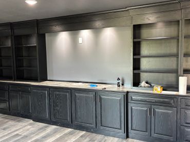 Empty dark wood cabinets and shelves with marble countertop.