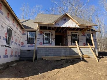 New house under construction with visible framing and lumber wrap.