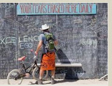 Man writing on a chalkboard wall that says "Your Fears Erased Here Daily".