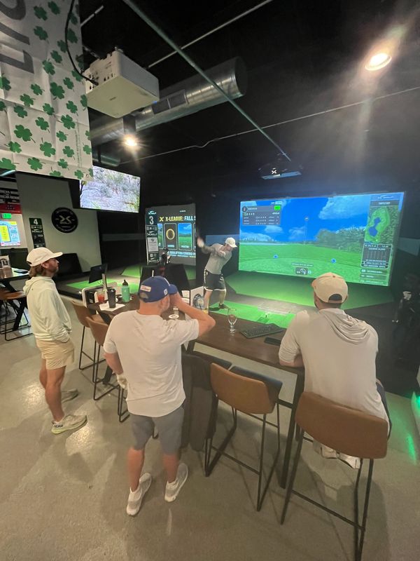 Group playing golf simulator indoors.