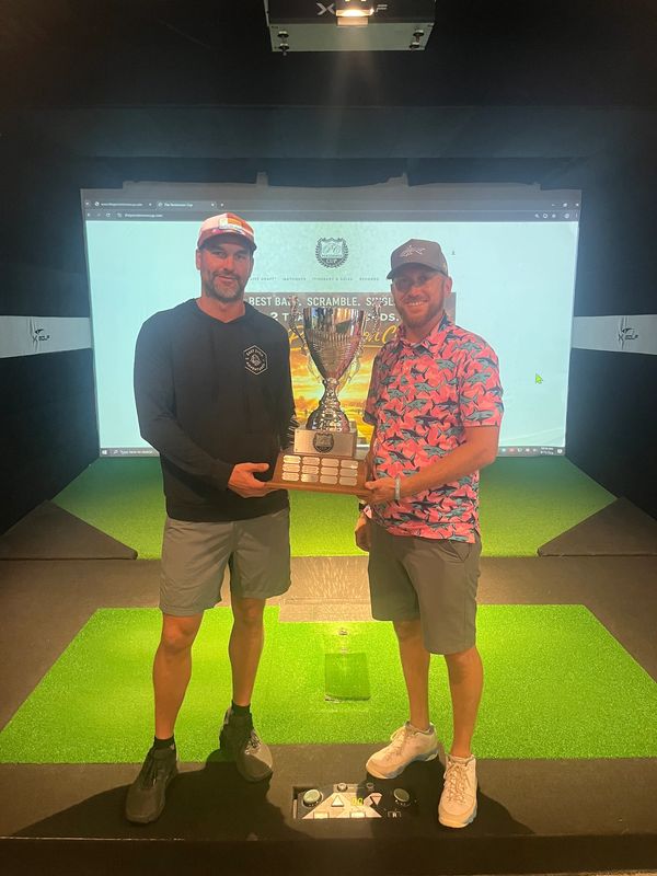 Two men holding a trophy together indoors.