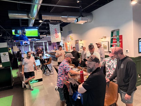 Group of men socializing indoors with sports on TV.