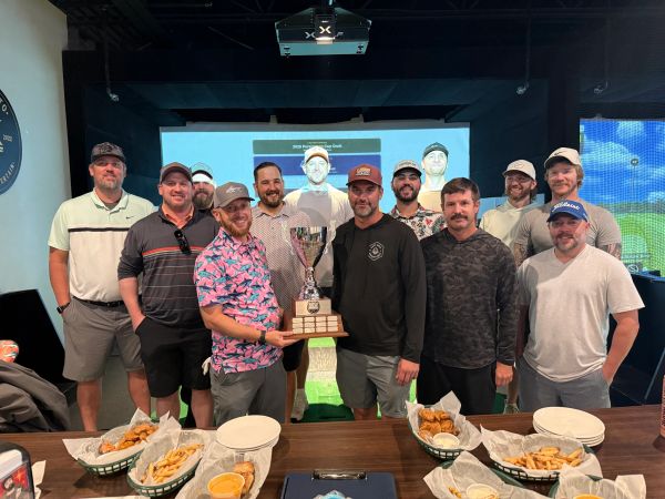 Group of men holding trophy behind a table with food.