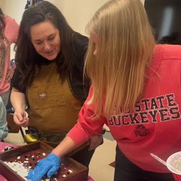 Two women engaged in an indoor craft activity.