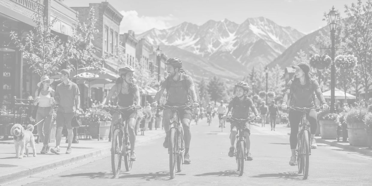 Family biking together on a sunny mountain town street.
