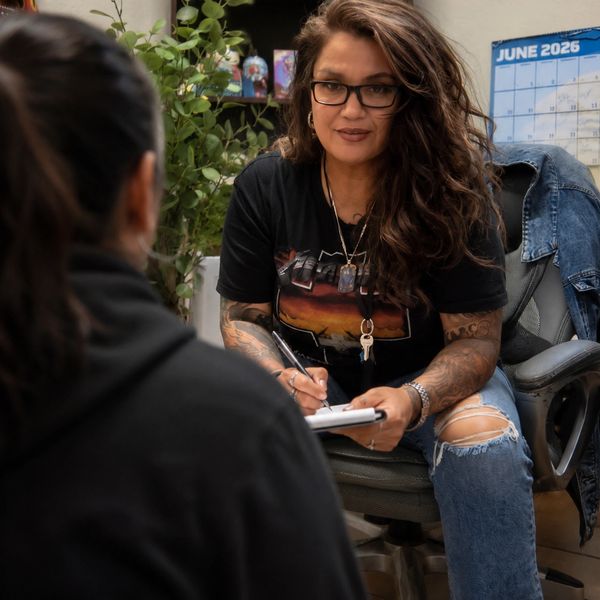 Woman taking notes while listening to another person.