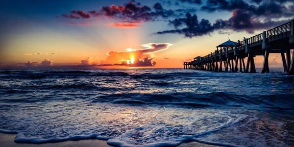 Sunset over the ocean with a pier extending into the water.