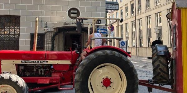 A person driving a red International tractor on a city street.
