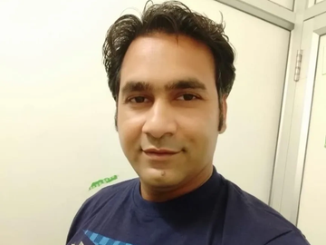 Man with dark hair wearing a navy blue shirt.