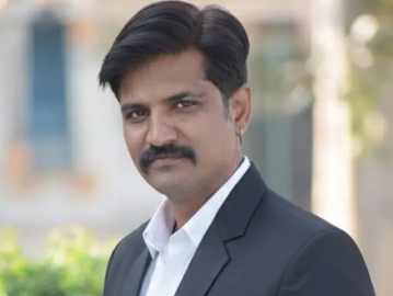 Man in a suit with a mustache outside.
