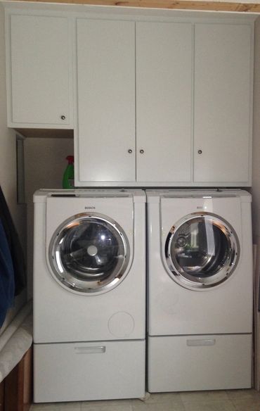 Two cloth dryer and white cabinets in the laundry room