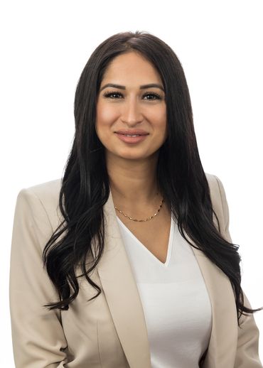 Professional woman with long dark hair in beige blazer and white top.