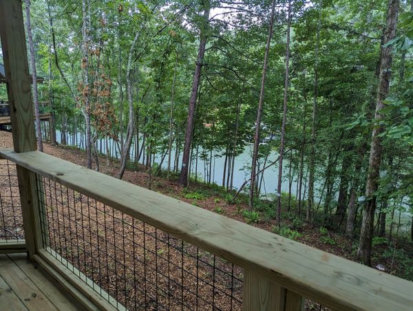View of a wooded area and a river from a wooden deck.