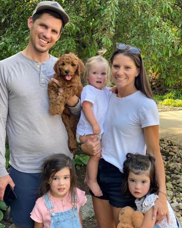 A happy family with three children and two dogs outdoors.