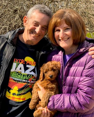 Happy couple holding an adorable fluffy puppy outdoors.