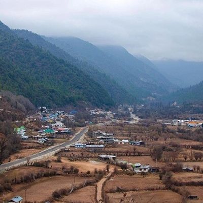 A valley town surrounded by mountains under a cloudy sky.