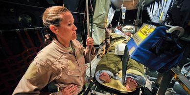 Military medical personnel attending to a wounded soldier inside a transport aircraft.