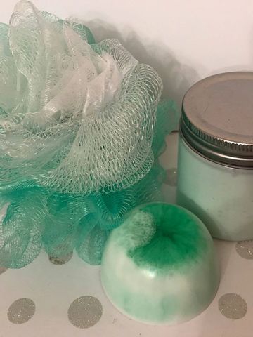 Green and white bath sponge with soap and a jar.