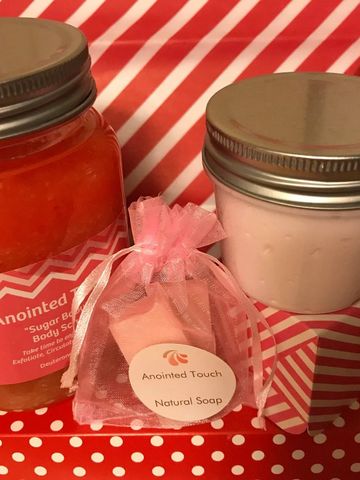 Pink-themed skincare products including body scrub, natural soap, and cream against red and white patterns.
