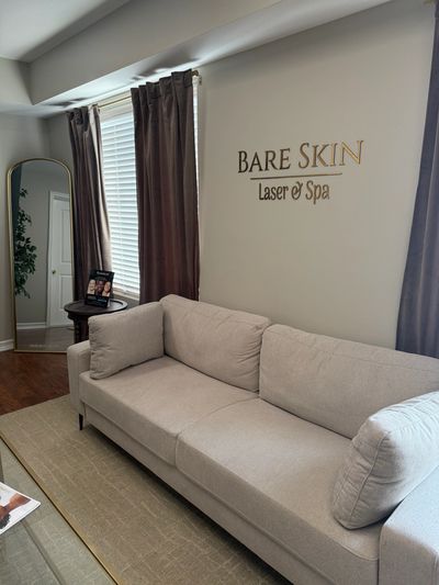 Cozy spa waiting area with beige couch and curtains.