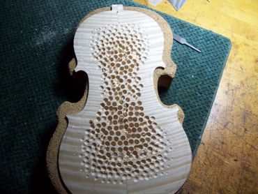 Guitar-making process showing body in shaping fixture
