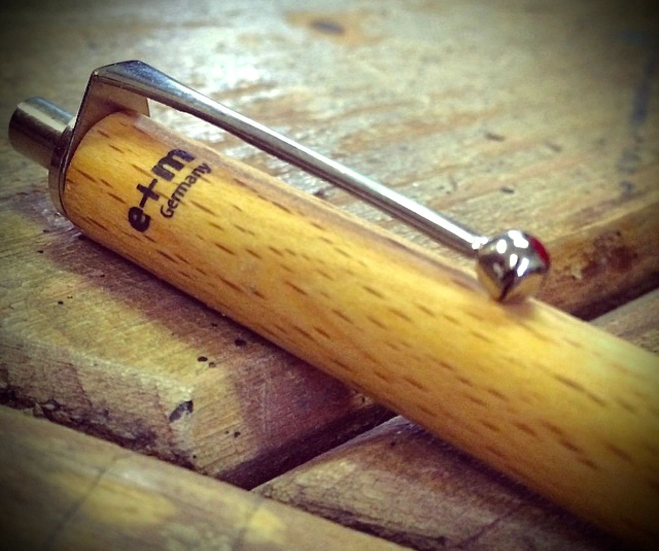Close-up of a wooden pen with metal clip on a wooden surface. J. R. Welch Writer