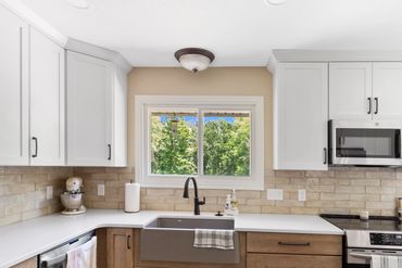 Modern kitchen with white and wood cabinets, farmhouse sink, and stainless steel appliances.