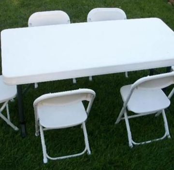 White folding table and chairs set on green grass.